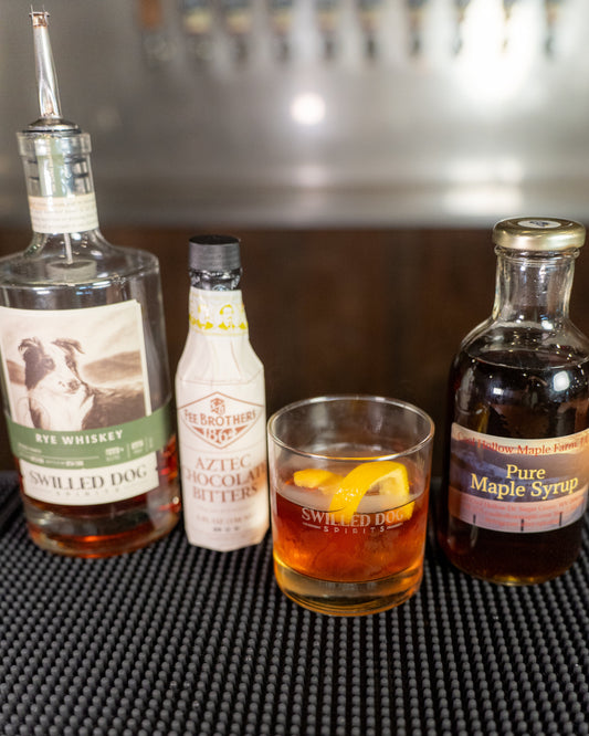Maple Old Fashioned cocktail garnished with an orange peel and cherry